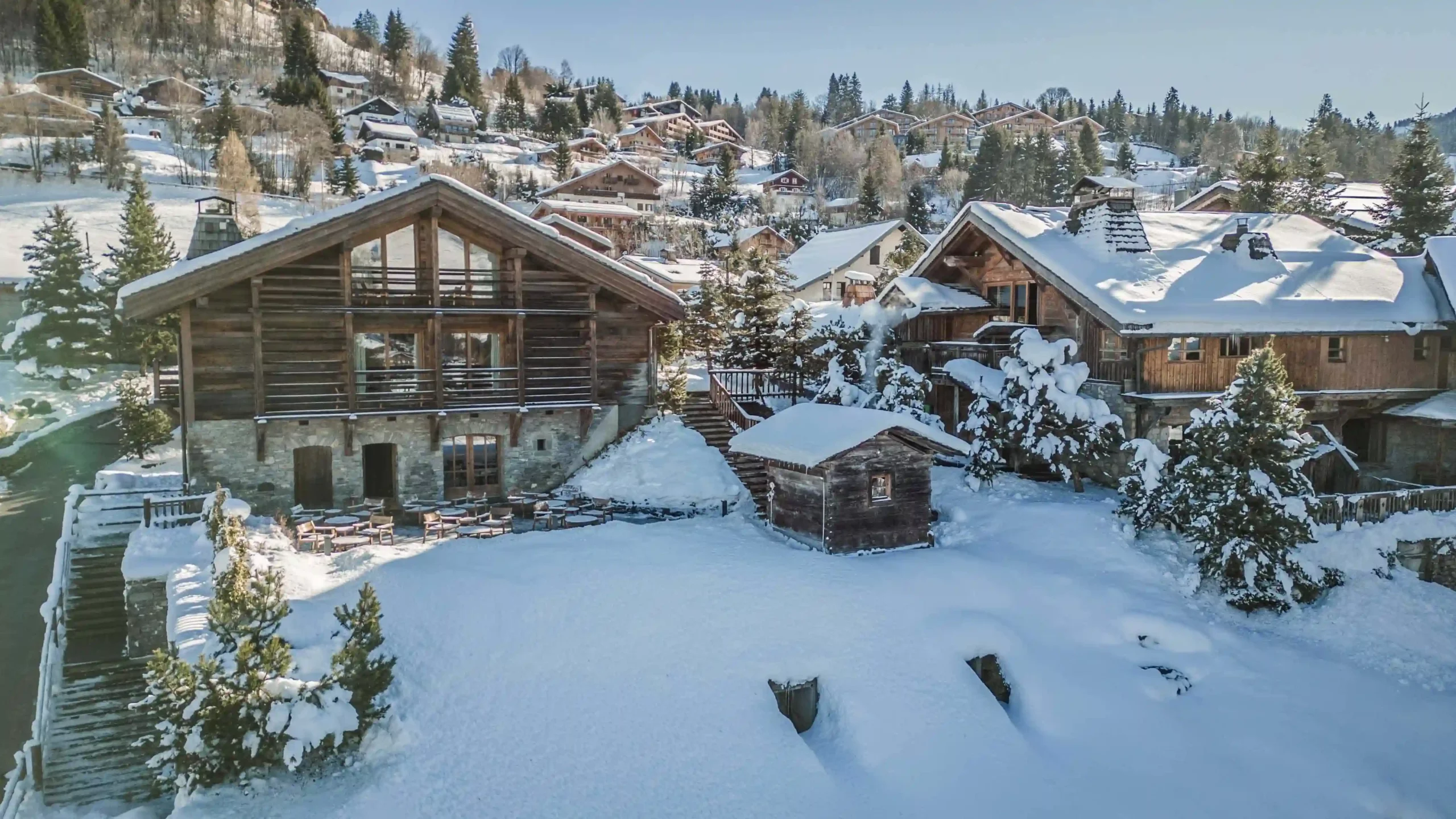 Zannier Le Chalet, Megève, France - Drone picture of the property featuring the three alpine chalets and the sunny terrace